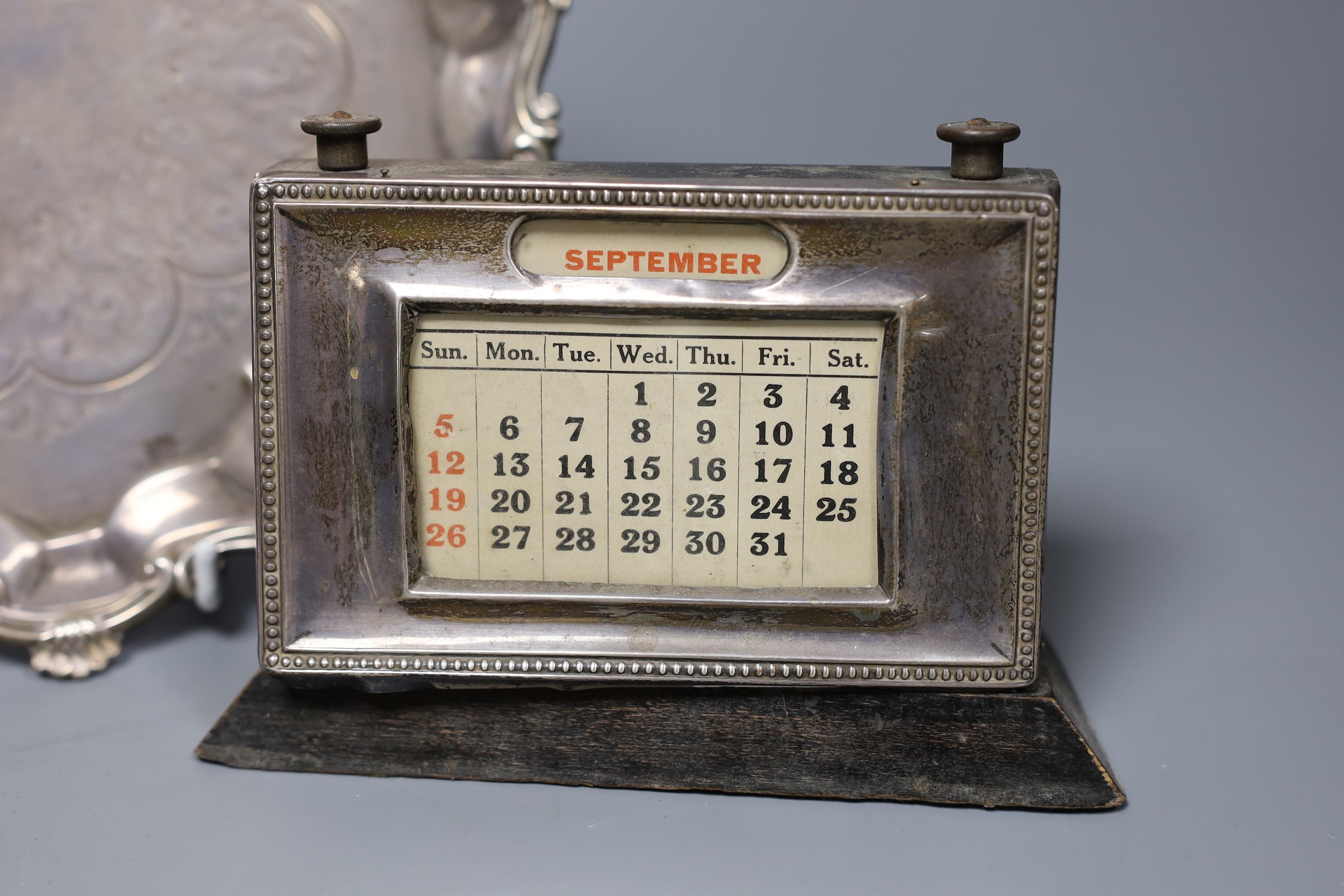 A Victorian silver waiter with scroll and piecrust border, London 1860, 23cm, 13 oz, a Victorian silver cream jug, 4.5oz and a later silver mounted desk calendar